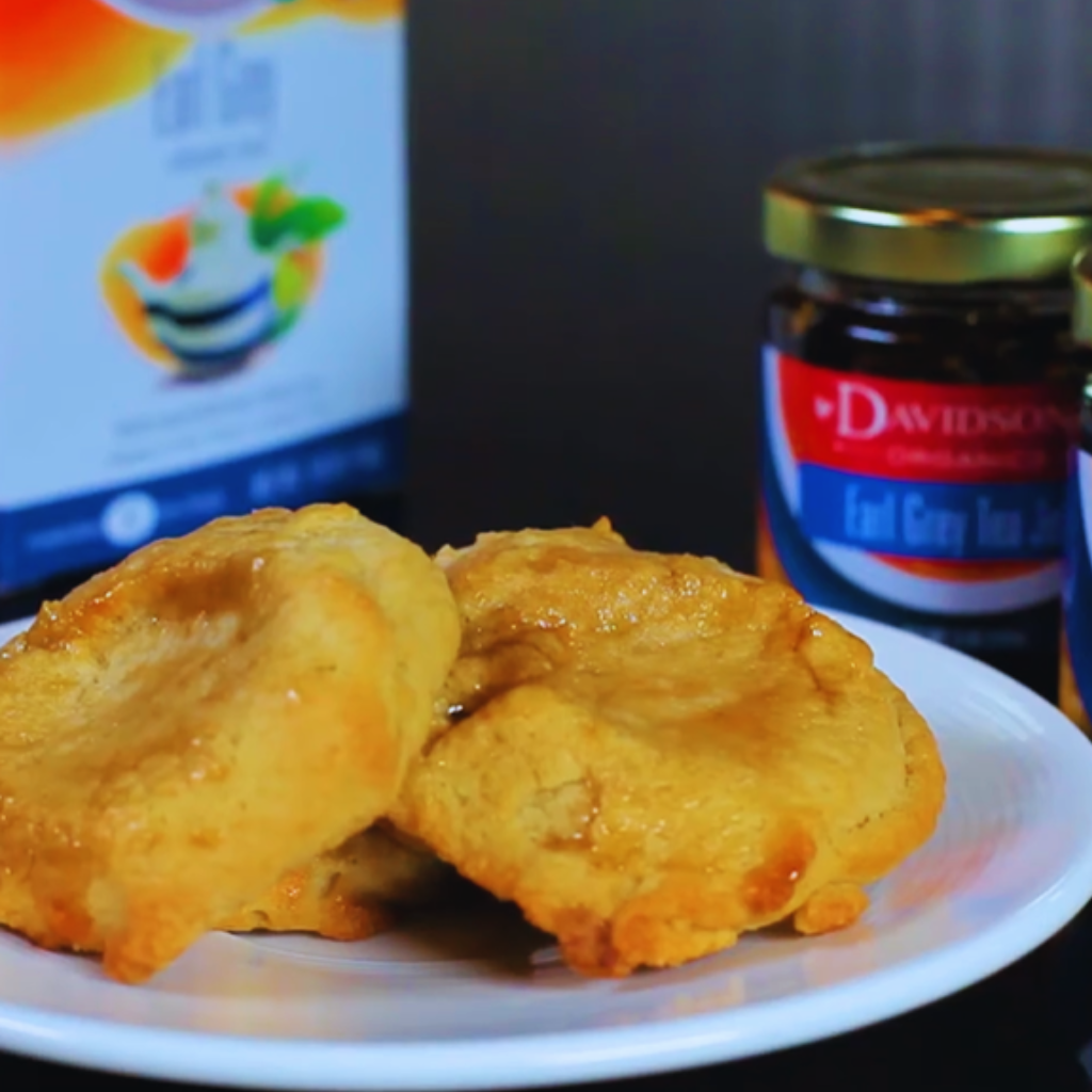 Two biscuits on a plate with a jar of jam and a box in the background