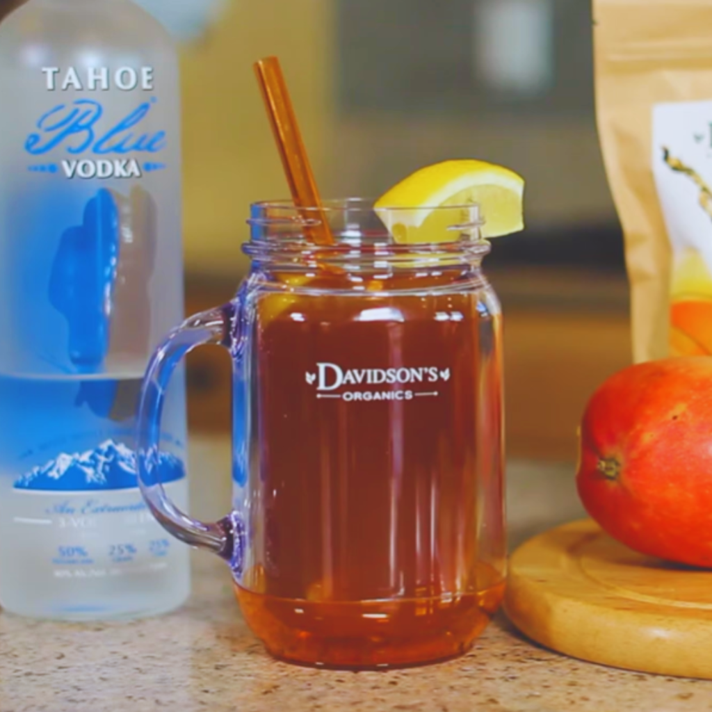 Mason jar with Davidson's Organics logo, Tahoe Blue Vodka bottle, and fruit on a countertop.