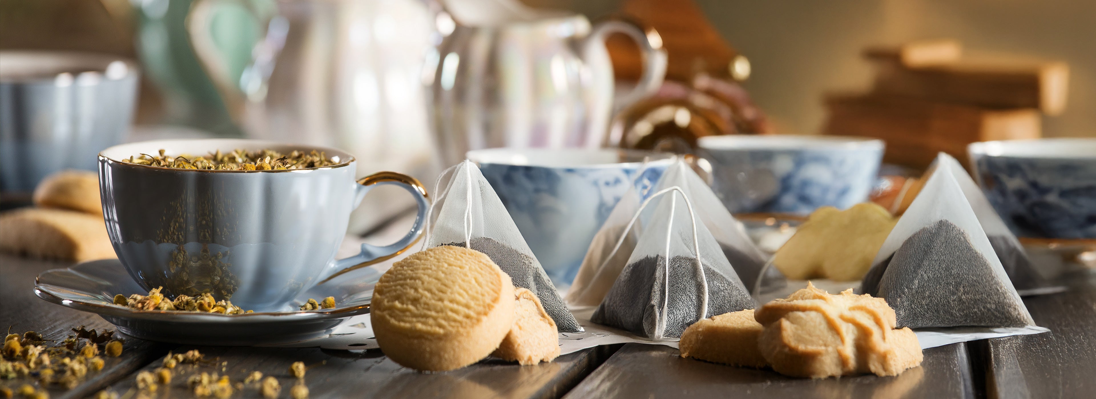 Tea cups, teabags, and cookies on a wooden surface with a blurred background