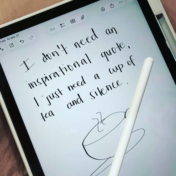 A close-up of a tablet screen showing handwritten text that reads, 'I don't need an inspirational quote, I just need a cup of tea and silence.' A white stylus rests across the lower right of the screen, with a white tablet case visible around the edges.
