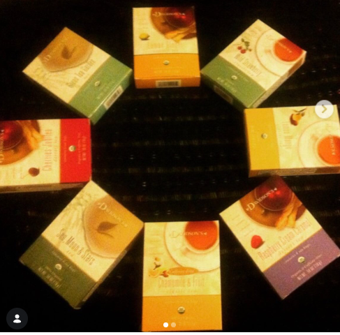 Eight boxes of Darjeeling tea arranged in a circle on a dark surface, showing different flavor variants with colorful packaging.