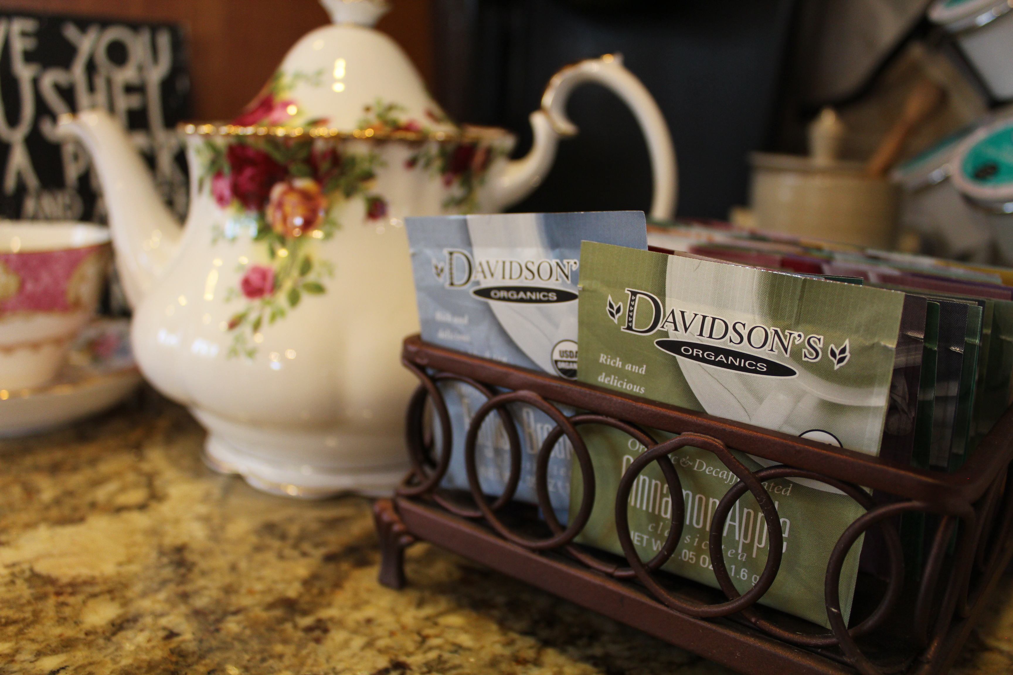 Davidson's Tea bags displayed in a dispenser with teacups and a teapot.

