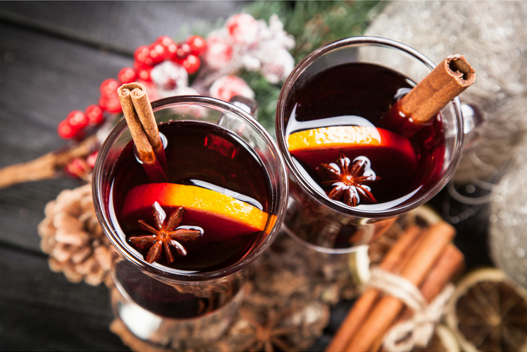 Two glasses of mulled wine with orange slices and cinnamon sticks.