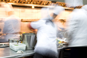 Blurred chefs working in a busy stainless steel professional kitchen.