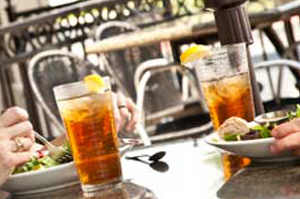 People enjoying iced tea and meals at an outdoor cafe table.